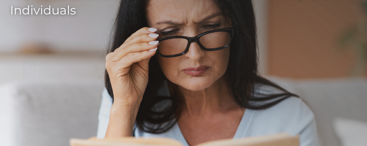 Middle-aged woman struggling to read a book due to presbyopia, before Refractive Lens Exchange